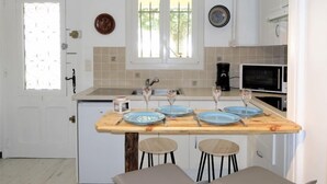 A compact kitchen with a wooden island, white cabinets, a microwave, and a coffee maker. - Le Mas Kilou by Interhome (Saint Aygulf)
