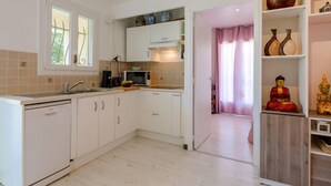 A modern kitchen with white cabinets, a microwave, and a sink. There is a shelf with decorative items and a statue. - Le Mas Kilou by Interhome (Saint Aygulf)