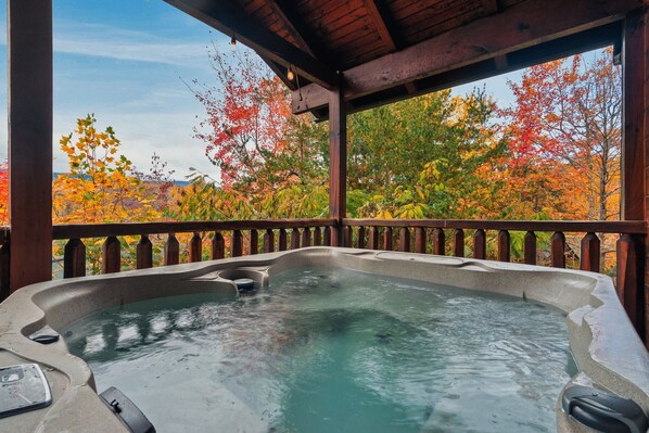 Relax in a hot tub under a shaded pergola surrounded by trees.