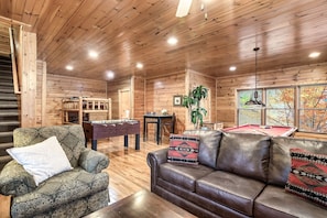 Relax in a warm and inviting space with a leather sofa, plush armchair, and billiards table.