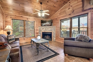 Cozy cabin interior with a comfortable seating area, fireplace, and large windows.