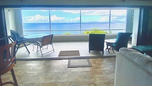 Un balcón amplio con vistas al océano, amueblado con una mesa, sillas y un sofá.