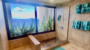Un baño con un ventanal grande, una ducha y un tapete verde.