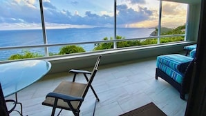 Un balcón con vistas al mar, una mesa de vidrio y un sofá.