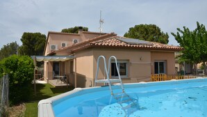 Une maison avec une piscine, un patio couvert et une antenne parabolique.