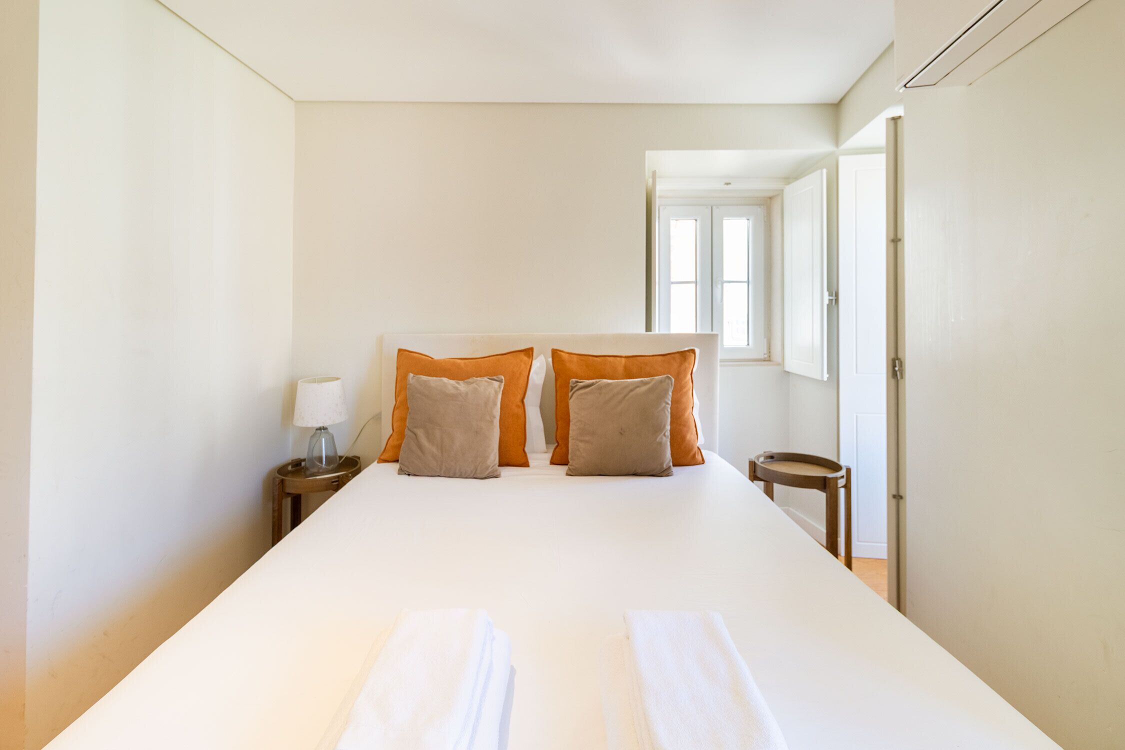 A hotel room with a large bed, two nightstands, a lamp, and a window with curtains.