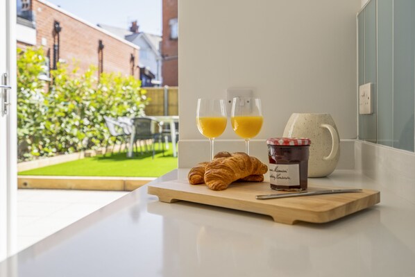 A breakfast setup with croissants, orange juice, and jam on a kitchen counter.