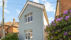 Ein zweigeschossiges Haus mit Satteldach, einer Veranda und einem kleinen Vorgarten.