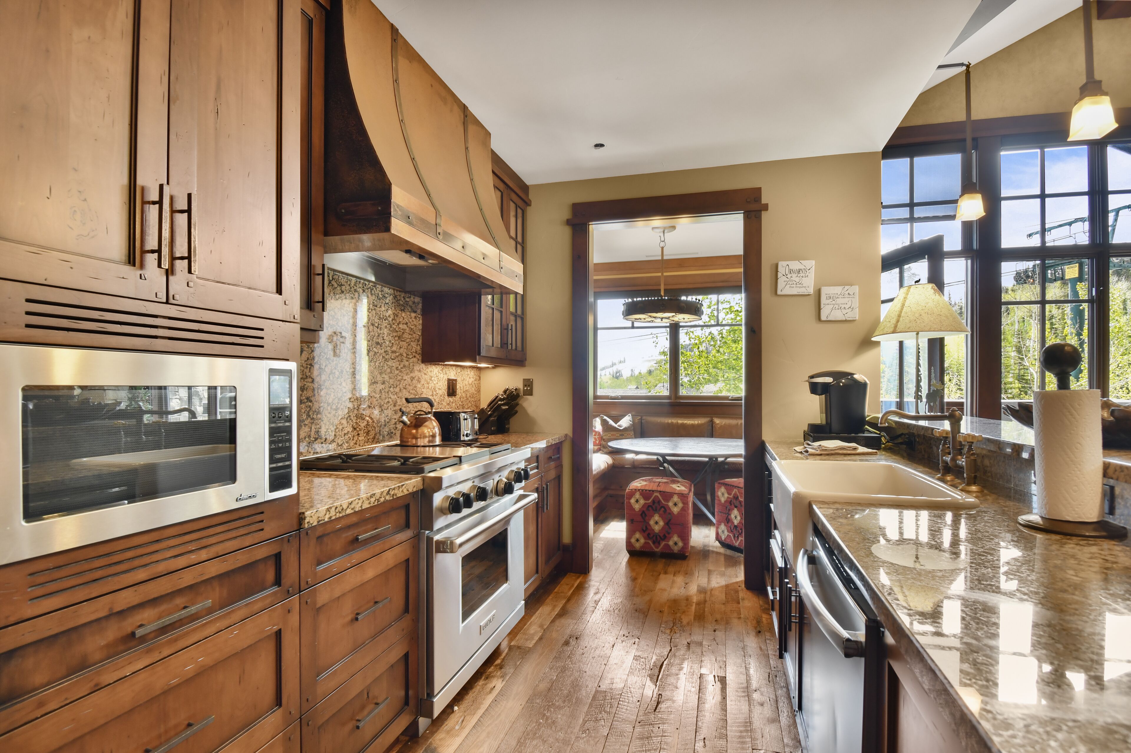 A kitchen with wooden cabinets, a stainless steel oven, granite countertops, and a large window providing natural light.