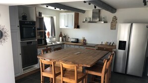 A kitchen with a wooden dining table, four chairs, a refrigerator, and a stove. - Ancienne Ferme Rénovée Entièrement , Dans la Campagne Aixoise (Venelles)