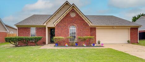 A single-story brick house with a gabled roof, a front door, and a garage.