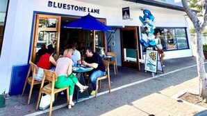 A building with 'BLUESTONE LANE' signage, outdoor seating, and 'UNIT 2' and 'UNIT 3' labels on the facade. - Coastal hideaway w/ beach access & workspace (San Clemente)