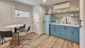 A compact kitchen with a round table and four chairs, a microwave, a refrigerator, and a sink. - Coastal hideaway w/ beach access & workspace (San Clemente)