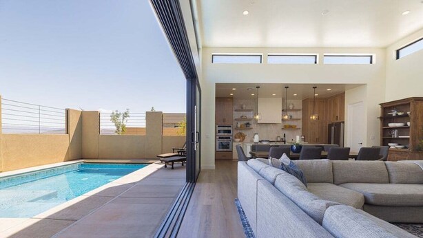Un espacio de estar moderno con piscina, un sofá grande y una zona de cocina.