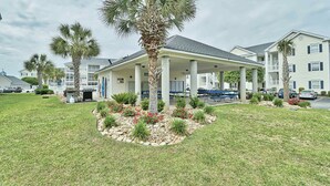 A hotel with a covered patio, palm trees, and a landscaped garden.