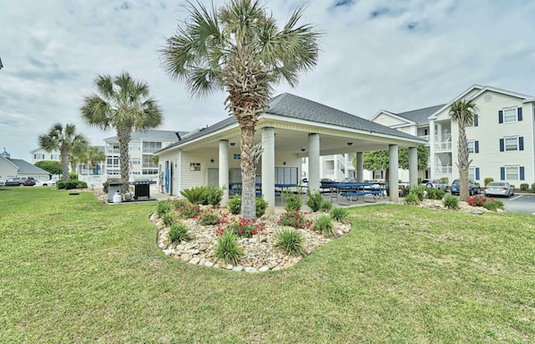 A hotel with a covered patio, palm trees, and a landscaped garden.