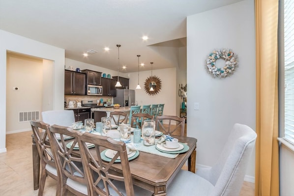 A dining area with a wooden table, chairs, and a kitchen in the background.