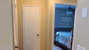 Un pasillo con suelo de madera, una puerta blanca e iluminación en el techo.
