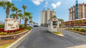 Un estacionamiento con un letrero que dice Royal Palms, palmeras y un edificio de varios pisos al fondo.