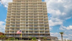 Un hotel alto de varios pisos con balcones, situado cerca de una playa.