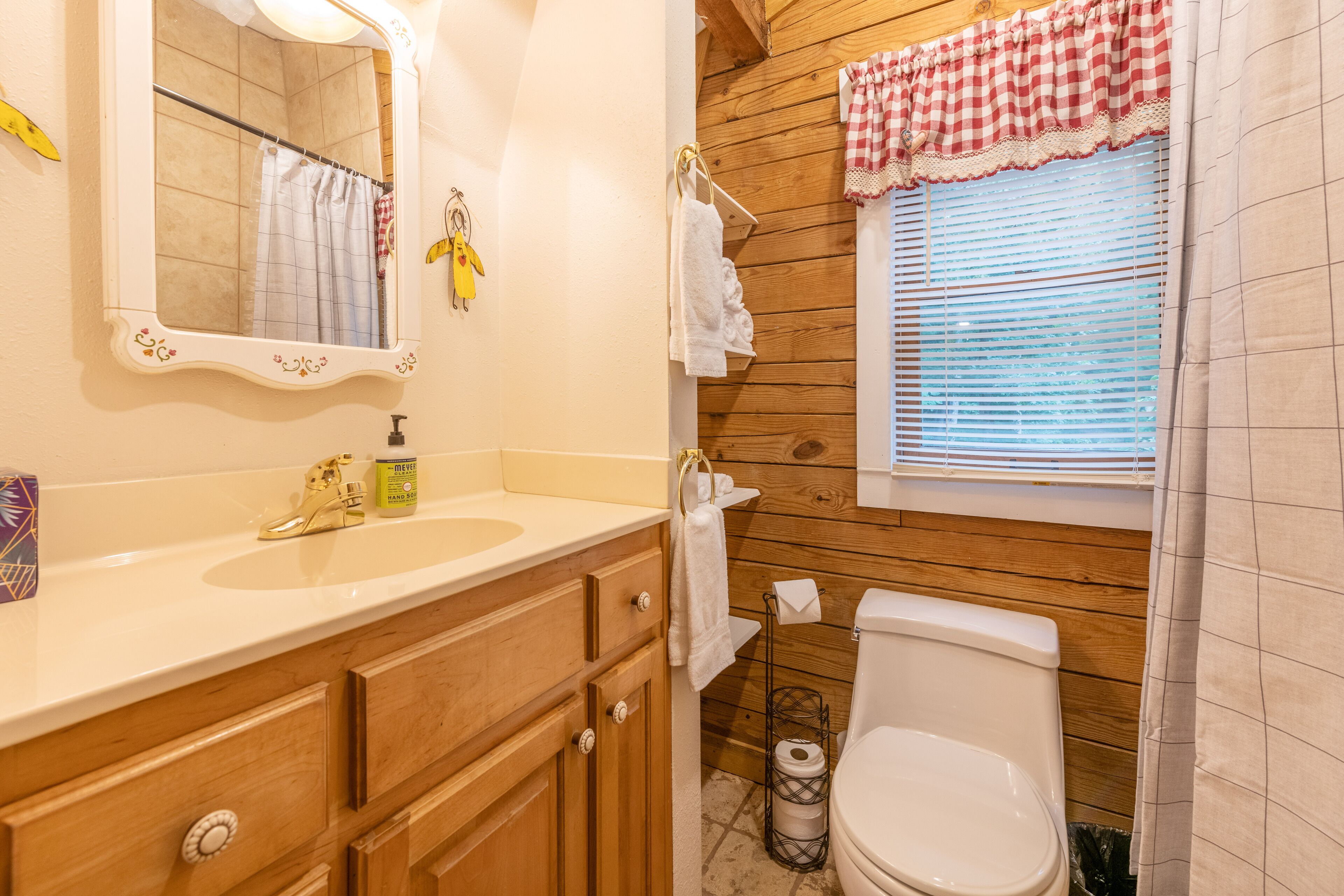 Un baño con tocador de madera, un espejo, un lavabo y un inodoro.