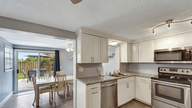A modern kitchen with white cabinets, stainless steel appliances, and a dining area with a table and chairs.
