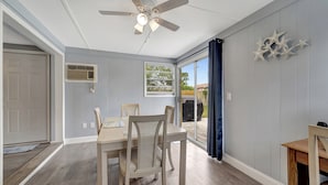 A dining area with a table and chairs, a ceiling fan, and a view through a glass door.