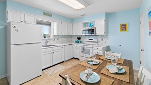 A modern kitchen with white cabinets, a refrigerator, microwave, and oven. - Cozy 2BR - 2BA Condo - Ocean, Marsh & ICW Views • Pool & Private Dock • Sleeps 6 (Ocean Isle Beach)