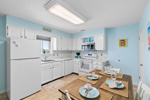 A modern kitchen with white cabinets, a refrigerator, microwave, and oven. - Cozy 2BR - 2BA Condo - Ocean, Marsh & ICW Views • Pool & Private Dock • Sleeps 6 (Ocean Isle Beach)