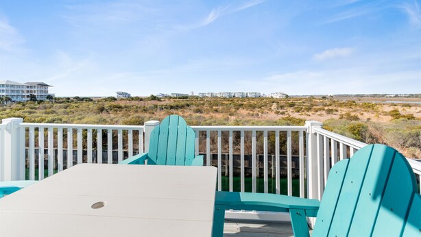 A deck with a view of a beach and buildings in the distance. - Cozy 2BR - 2BA Condo - Ocean, Marsh & ICW Views • Pool & Private Dock • Sleeps 6 (Ocean Isle Beach)