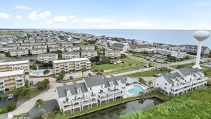 A coastal residential area with multiple apartment buildings, a large water tower, and a swimming pool. - Cozy 2BR - 2BA Condo - Ocean, Marsh & ICW Views • Pool & Private Dock • Sleeps 6 (Ocean Isle Beach)