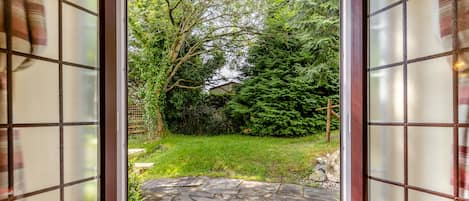 A view through a glass door with a stone pathway leading to a green garden area.