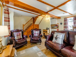 A cozy living room with leather armchairs, a wooden staircase, and a kitchen in the background. - Lavender Cottage - UKC6677 (Betws Yn Rhos)