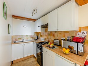 A compact kitchen with white cabinets, a stove, a sink, and a toaster. - Lavender Cottage - UKC6677 (Betws Yn Rhos)