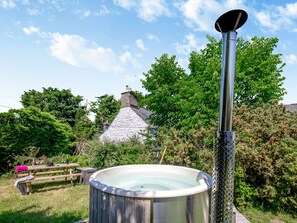 A hot tub with a metal pole, a picnic table, and a stone-roofed building in the background. - Lavender Cottage - UKC6677 (Betws Yn Rhos)
