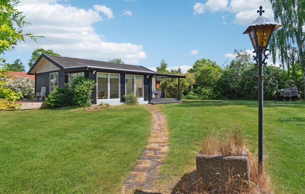 A modern house with a covered porch, a stone pathway leading to the entrance, and a lawn with a lamp post. - Cozy home in Kirke Hyllinge with WiFi (Kirke Hyllinge)