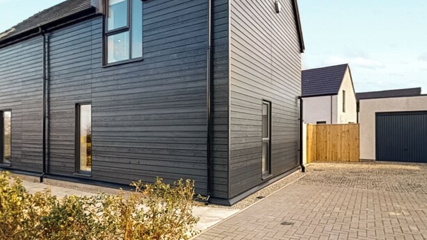A modern two-story building with a dark exterior, large windows, and a brick-paved driveway. - 3 bedroom accommodation in Croy, near Inverness (Croy, near Inverness)