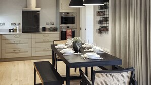 A modern kitchen with built-in appliances, a dining table set for four, and a black pendant light above. - 3 bedroom accommodation in Croy, near Inverness (Croy, near Inverness)