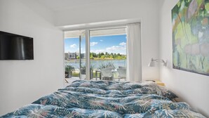 Una camera da letto con un letto grande, vista su un lago e un quadro appeso al muro.