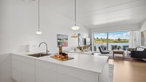 Una cucina moderna con un'isola grande, un'area pranzo con vista su un lago e un soggiorno con divano e tavolo.