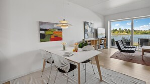 Un'elegante sala da pranzo moderna con un tavolo bianco, due sedie, un vaso con fiori e un quadro appeso al muro.