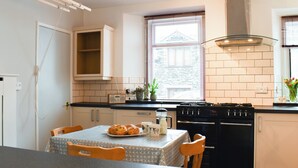 A kitchen with a dining table, chairs, a stove, oven, and a window with blinds.