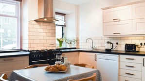 A modern kitchen with white cabinets, a black countertop, and a dining table set with a plate of croissants.