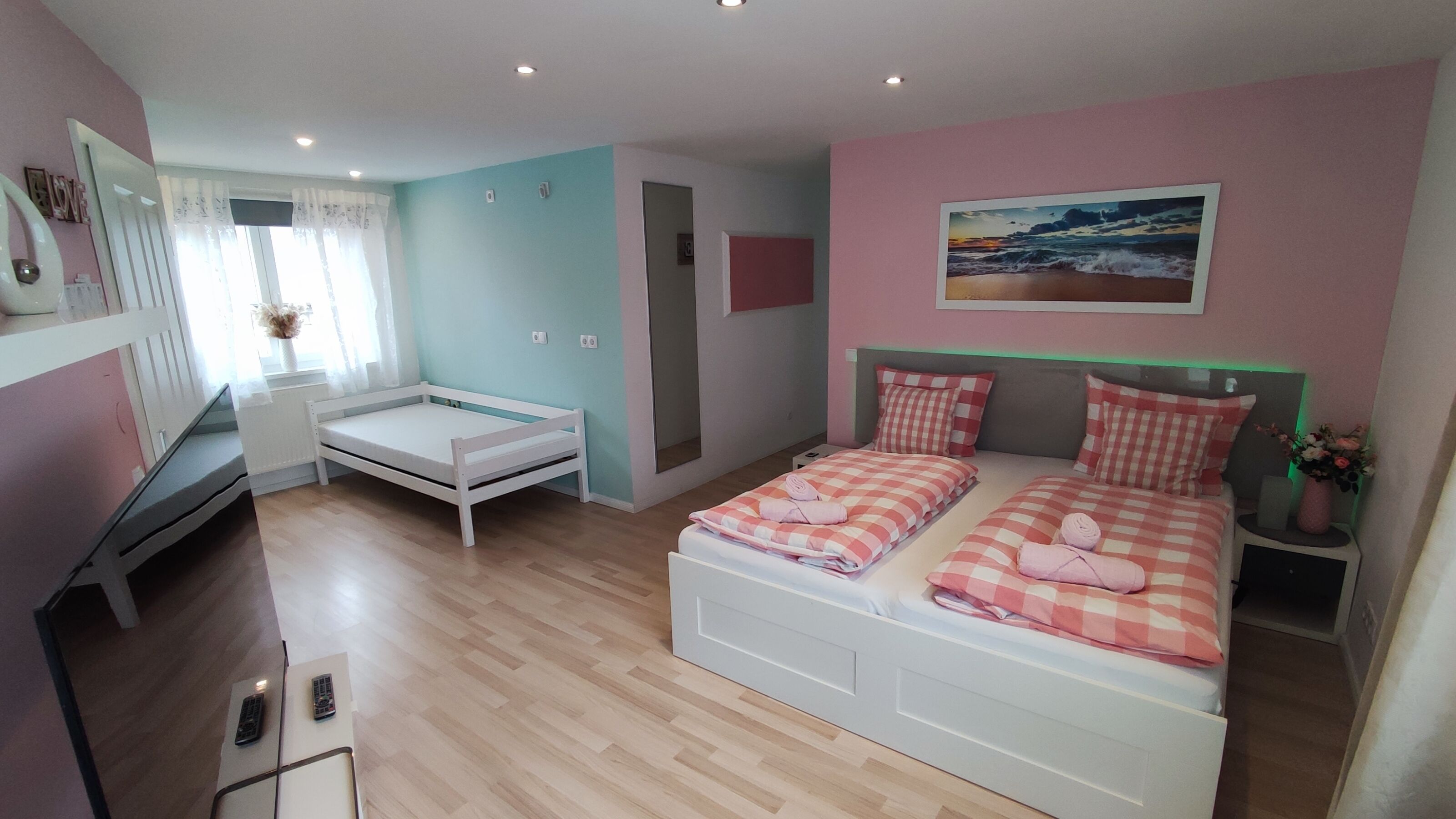 A bedroom with a bed, a desk, and a chair. There is a window with curtains and a painting on the wall.