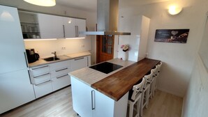 Une cuisine moderne avec des meubles blancs, un plan de travail en bois, une cuisinière encastrée et un évier.