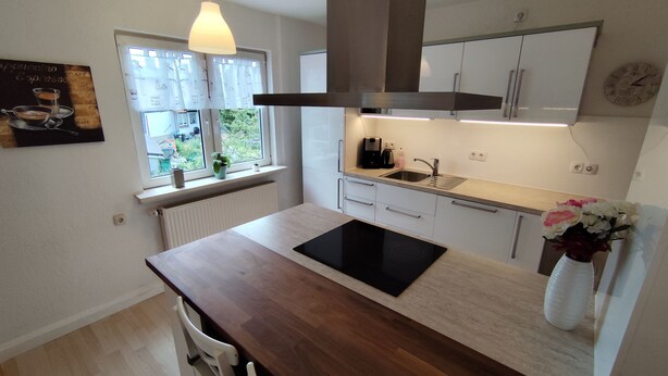 Une cuisine moderne équipée d’une cuisinière intégrée, d’un évier et d’une fenêtre avec des rideaux.