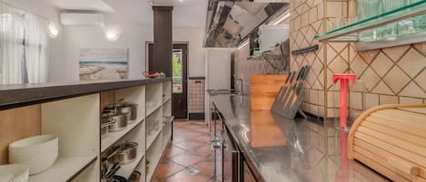 A modern kitchen with stainless steel appliances, a tiled backsplash, and a wooden countertop.