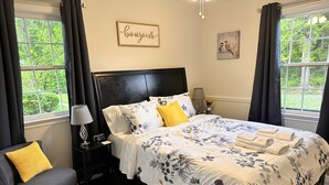 Une chambre à coucher avec un lit, des tables de chevet, une chaise et des rideaux.