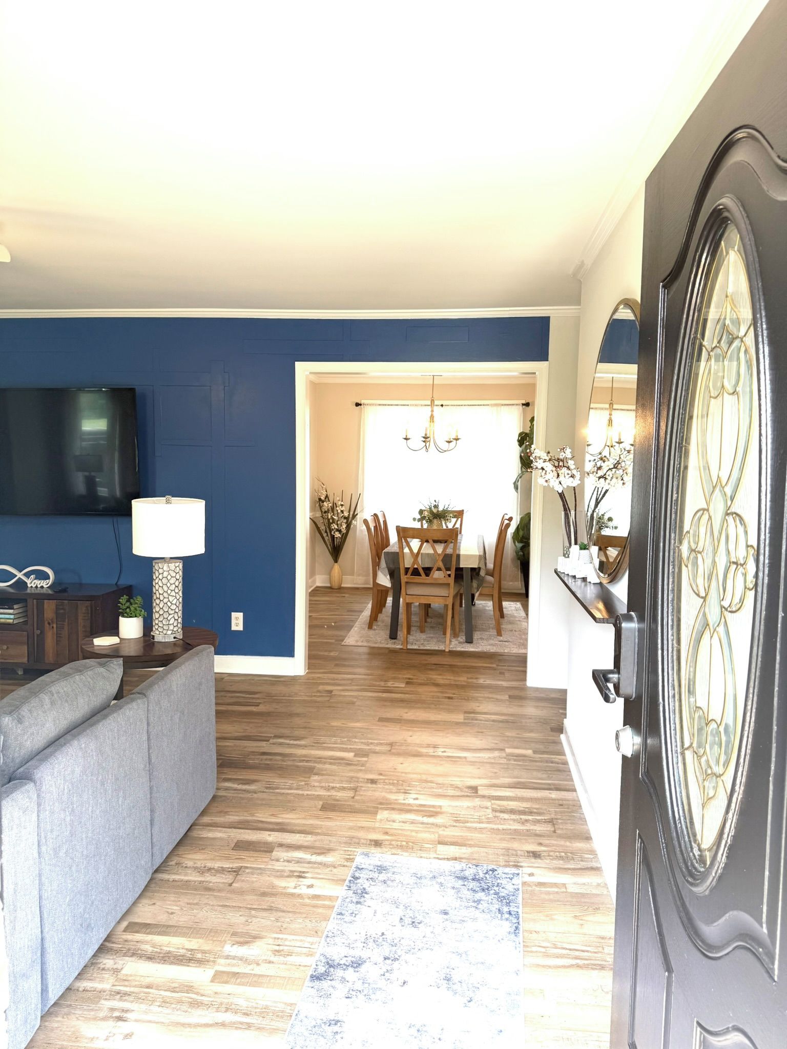 A living room with a sofa, a television, and a dining area with a table and chairs.