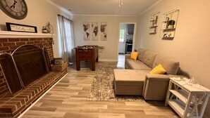 Un salon avec une cheminée, un canapé, une table basse et un baby-foot.